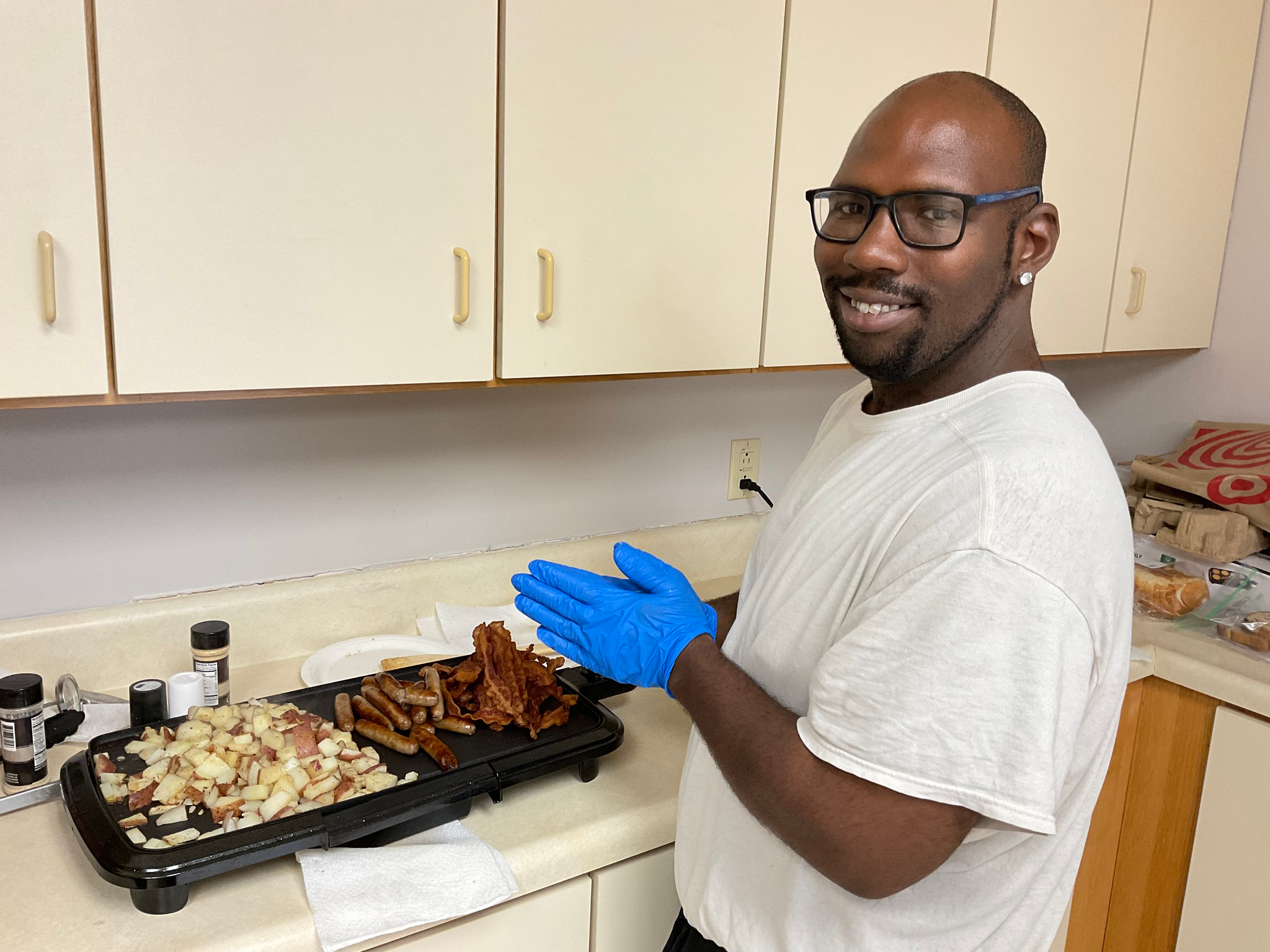 Photo of UES program participant Kayson cooking sausage and potatoes on a griddle