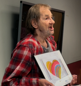 Lynne Jernigan describes his heart-shaped artwork to his peers at Ithaca Day Hab during the group’s sharing of gratitude.