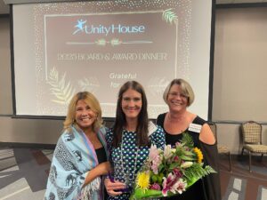 CEO Liz Smith (left) and COO Darlene Podolak (right) stand alongside 2025 Open Arms awardee and executive director of Nick's Ride 4 Friends, Ashley Moench.